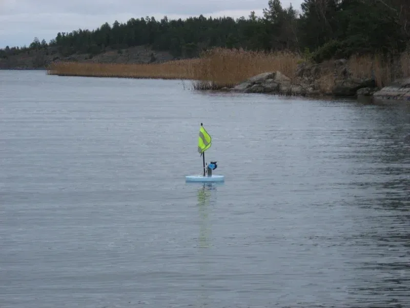 Flytande markering med flagga på vattnet nära en strand